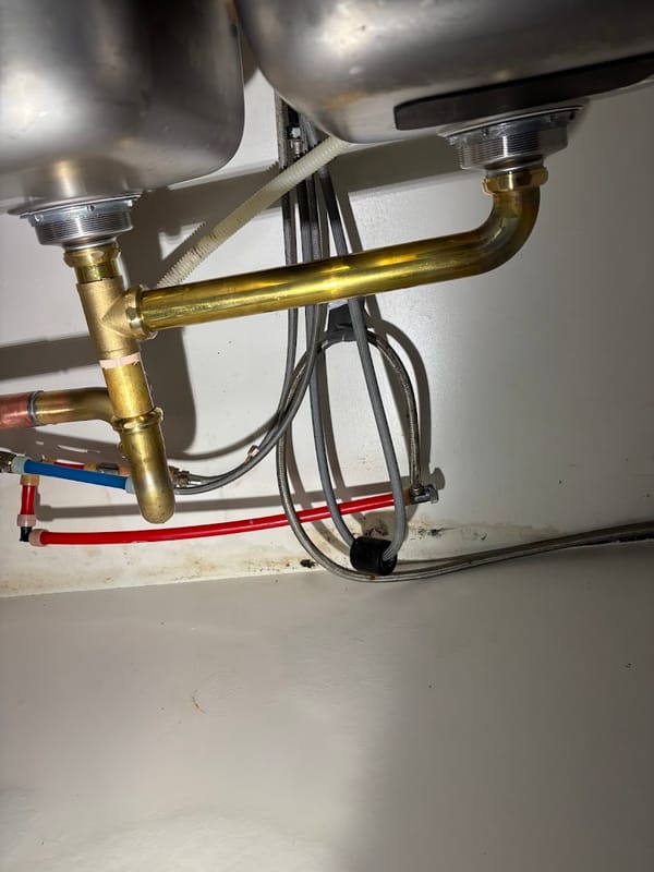 Brass drain assembly installed under a double kitchen sink